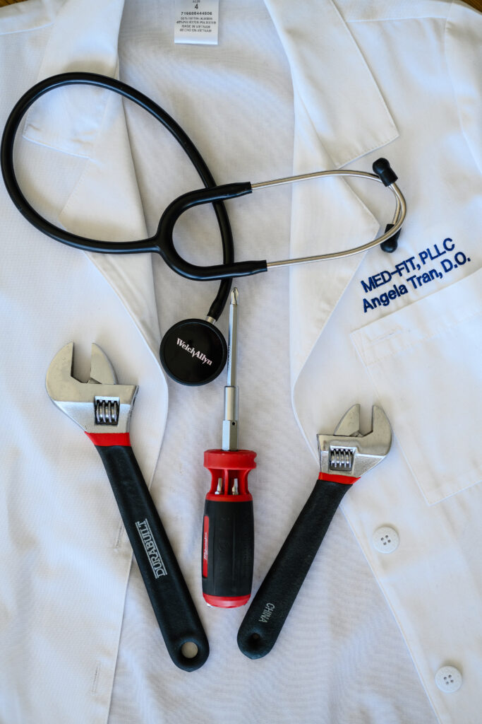 Dr. Tran’s white coat embroidered “Med-Fit, PLLC, Angela Tran, D.O.” with a stethoscope, two wrenches and a screwdriver