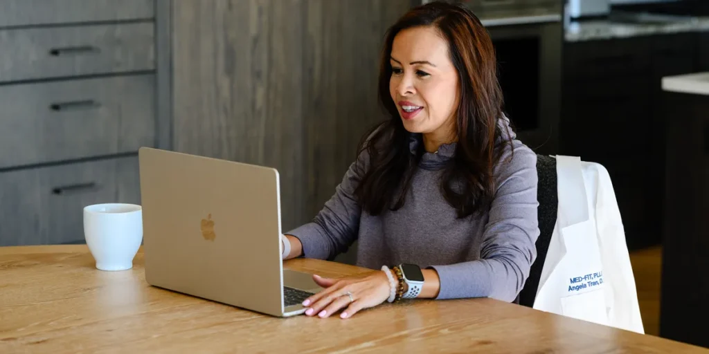 Dr. Angela Tran, DO working on a laptop at her kitchen table